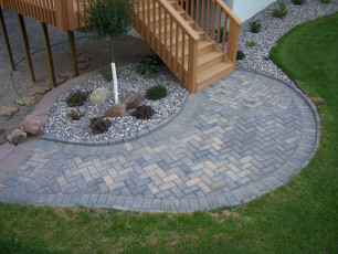 grey patio at bottom of stairs from deck at West Fargo, ND home by Oasis Landscapes