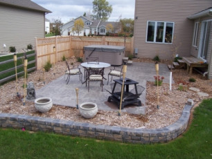 patio with fire feature and hot tub at Fargo, ND home by Oasis Landscapes