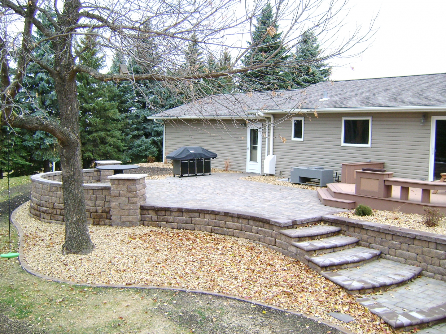Raised patio with paver stair system by Oasis Landscapes in West Fargo
