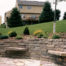 Large stone retaining wall landscape with sitting stones and patio