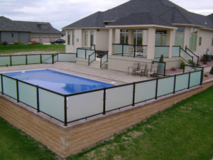 Safety rail with privacy panels around raise paver patio with pool